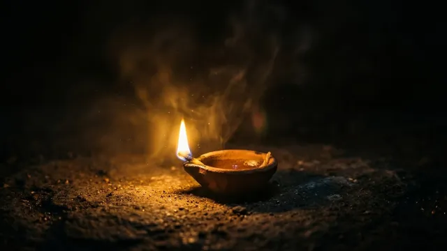 अंधेरे में रोशनी फैलाता हुआ एक दीपक